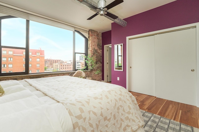 bedroom featuring a closet, a ceiling fan, multiple windows, and wood finished floors