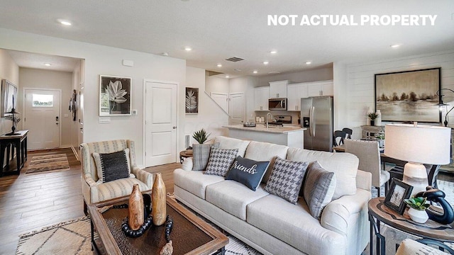 living room featuring visible vents, light wood-style flooring, and recessed lighting