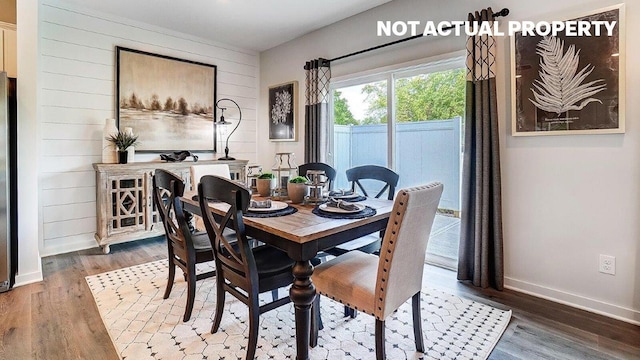 dining room with baseboards, wood walls, and wood finished floors