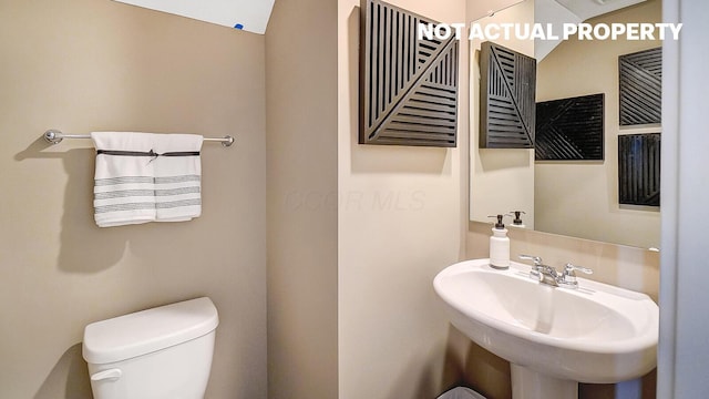 half bathroom featuring toilet and a sink