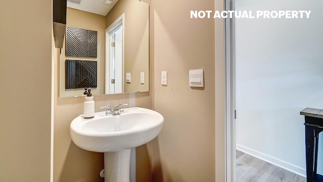bathroom with baseboards, visible vents, and wood finished floors