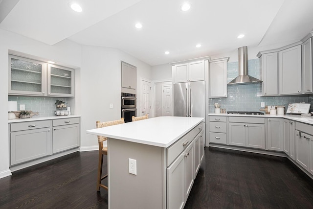 382 Beecher Rd, Columbus, OH 43230 - kitchen featuring wall chimney range hood, stainless steel appliances, gray cabinets, a breakfast bar, and recessed lighting