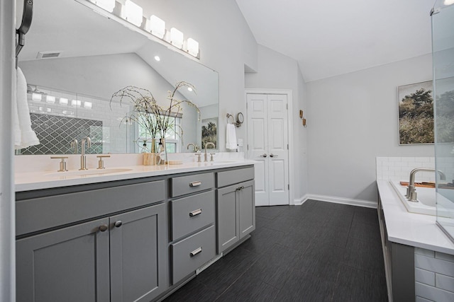 382 Beecher Rd, Columbus, OH 43230 - bathroom featuring double vanity, a bath, baseboards, high vaulted ceiling, and decorative backsplash