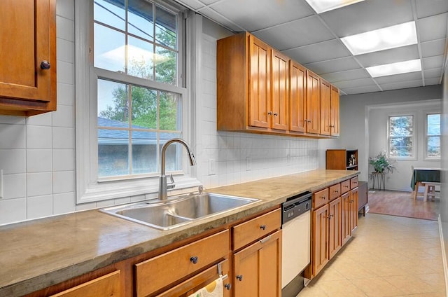 668 Enfield Rd, Columbus, OH 43209 - kitchen featuring dishwasher, a sink, brown cabinetry, decorative backsplash, and a paneled ceiling