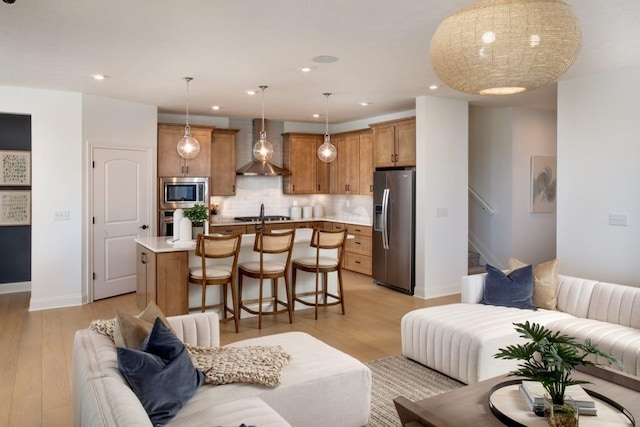 living area with baseboards, light wood finished floors, and recessed lighting