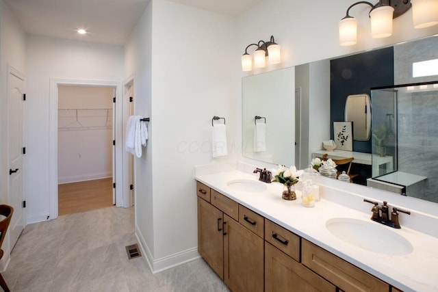 bathroom featuring a shower stall, visible vents, a sink, and a walk in closet