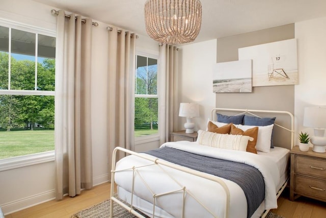 bedroom featuring a chandelier, wood finished floors, and baseboards