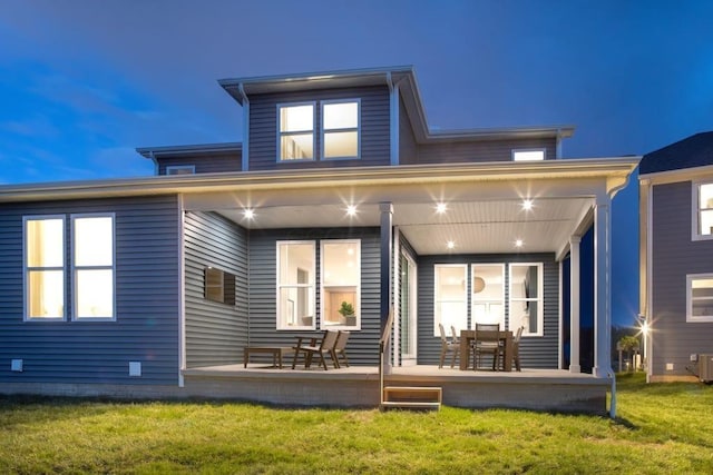 rear view of property featuring a porch, central AC unit, and a lawn