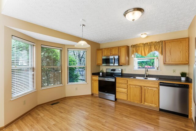 2099 Winding Hollow Dr, Grove City, OH 43123 - kitchen featuring a sink, dark countertops, stainless steel appliances, light wood-type flooring, and a wealth of natural light