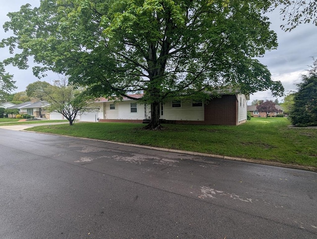 view of front of home with concrete driveway, an attached garage, and a front yard
