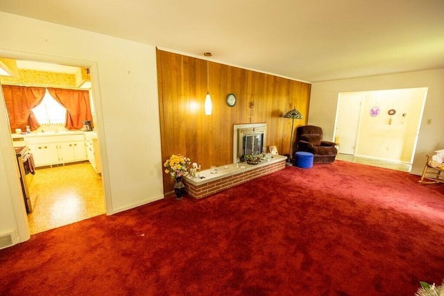 living room with carpet, wooden walls, and a brick fireplace