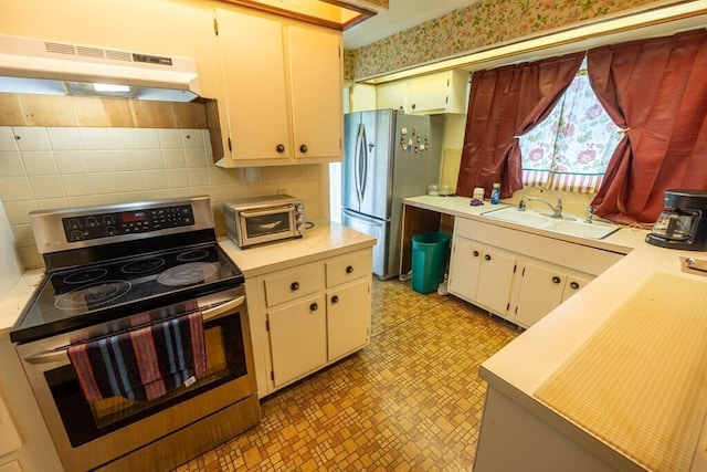 kitchen featuring light floors, stainless steel appliances, under cabinet range hood, a sink, and light countertops