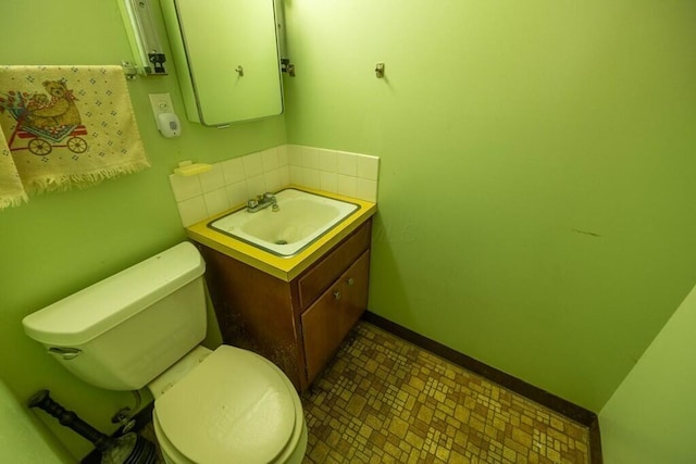 bathroom with backsplash, baseboards, vanity, and toilet