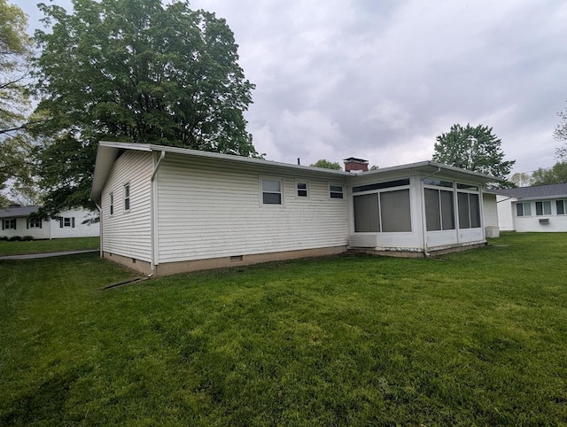 rear view of house with a sunroom, a yard, crawl space, and a chimney