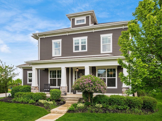 traditional style home featuring covered porch and a front lawn