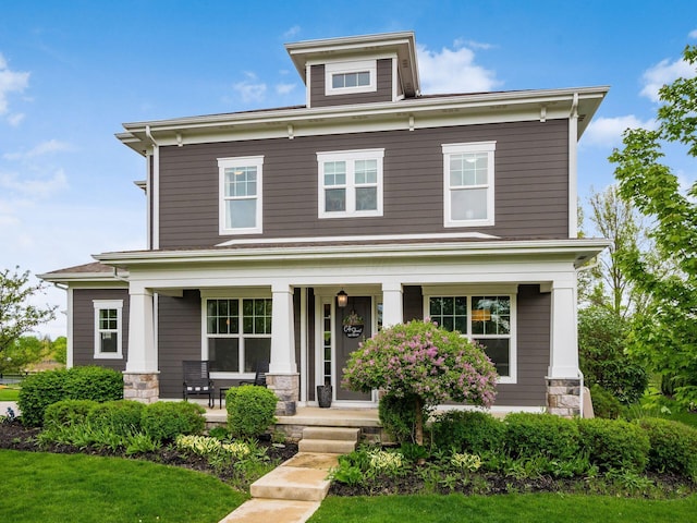 american foursquare style home featuring stone siding and covered porch