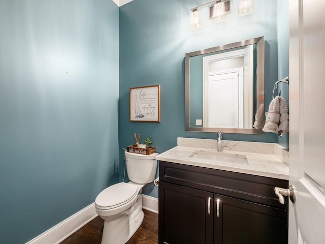 half bath featuring vanity, toilet, baseboards, and wood finished floors