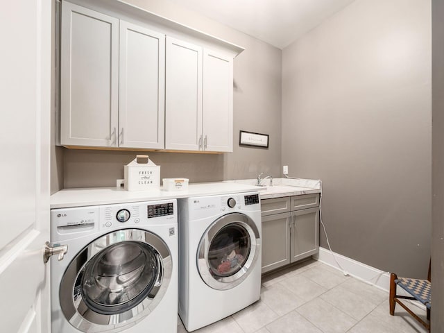 laundry area featuring washer and clothes dryer, a sink, cabinet space, light tile patterned floors, and baseboards