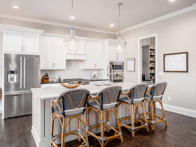 kitchen with a sink, tasteful backsplash, a kitchen island with sink, dark wood-style flooring, and appliances with stainless steel finishes