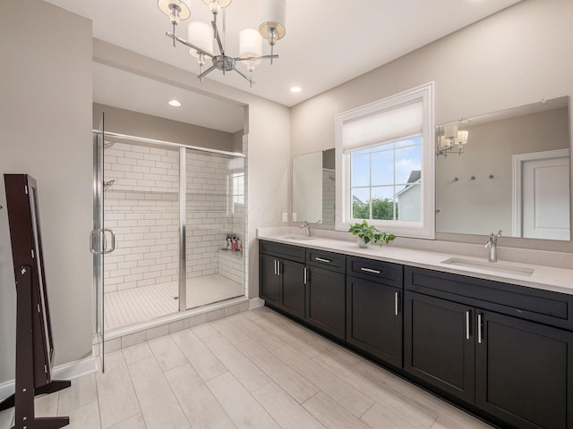 full bathroom with a sink, an inviting chandelier, double vanity, and a shower stall