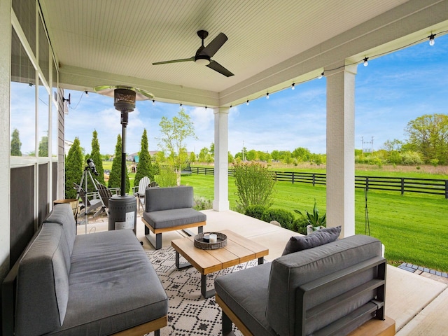 view of patio featuring an outdoor hangout area, a rural view, a ceiling fan, and fence