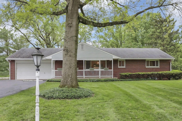 ranch-style house featuring brick siding, a garage, a front lawn, covered porch, and driveway