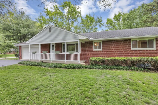 ranch-style house featuring brick siding, covered porch, an attached garage, and a front yard