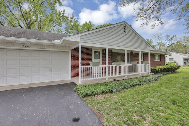 view of front of property featuring a porch, brick siding, driveway, and a front yard