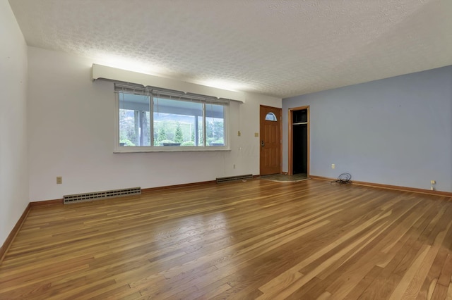 empty room with wood finished floors, a textured ceiling, and baseboards