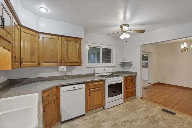 kitchen with white appliances, ceiling fan, brown cabinetry, and a sink