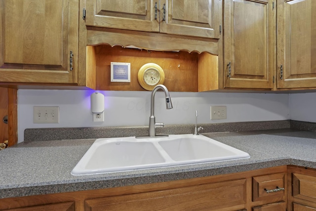 kitchen view of a sink, brown cabinets, and dark countertops