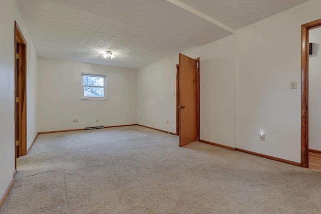 carpeted empty room with a textured ceiling and baseboards