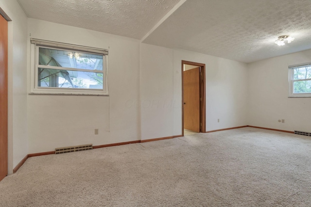 spare room with a textured ceiling, carpet flooring, and baseboards