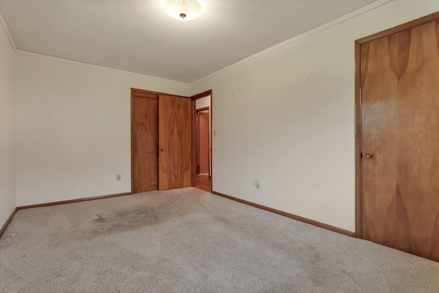 unfurnished bedroom with carpet floors, baseboards, a closet, and ornamental molding
