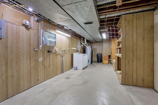 unfinished basement with wooden walls, washer / dryer, and water heater