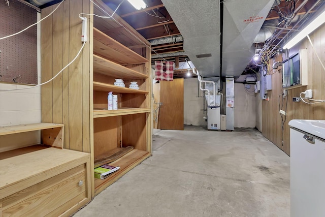 unfinished basement with refrigerator and heating unit