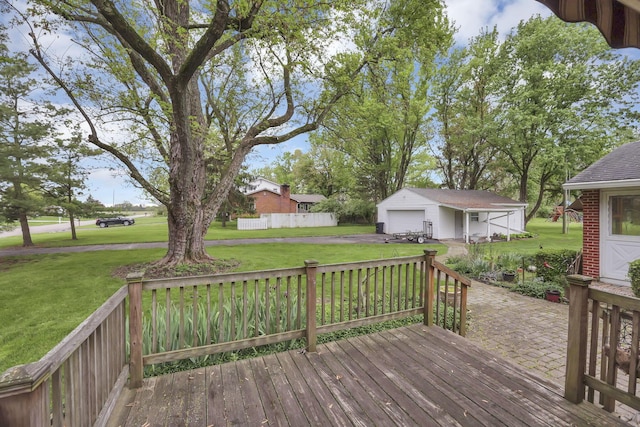 wooden deck featuring a yard, driveway, a detached garage, and an outbuilding