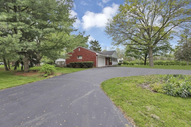 view of front facade with a garage, brick siding, a front lawn, and asphalt driveway