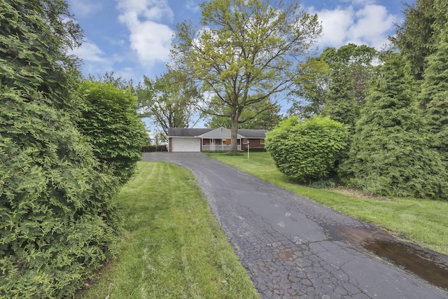 view of front facade with asphalt driveway, a front yard, and a garage