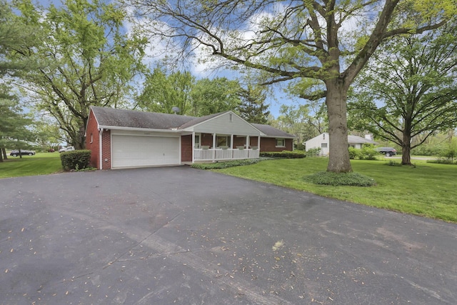view of front facade with a porch, brick siding, a front yard, asphalt driveway, and an attached garage
