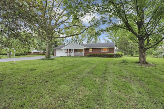ranch-style home featuring a garage, a front yard, brick siding, and driveway