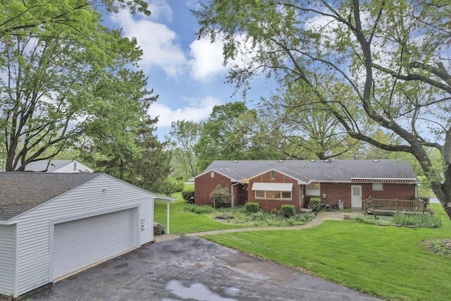 view of front facade featuring a front lawn, brick siding, driveway, an outdoor structure, and a garage