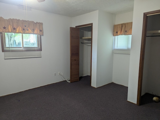 unfurnished bedroom featuring a textured ceiling, a closet, visible vents, and dark carpet