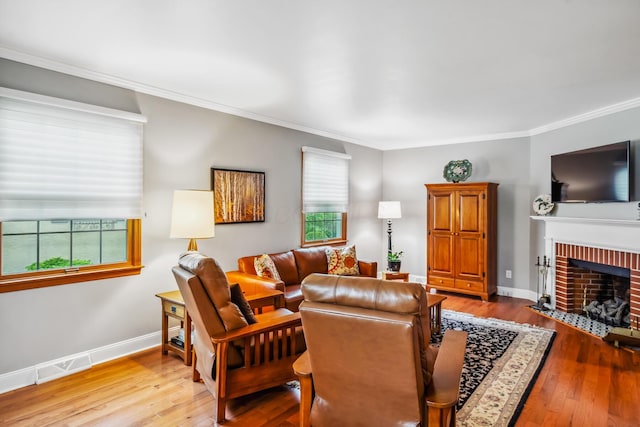 living room with crown molding, hardwood / wood-style floors, a brick fireplace, and baseboards