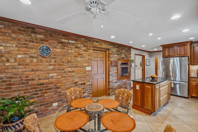 kitchen with stainless steel appliances, brick wall, light tile patterned floors, ceiling fan, and ornamental molding