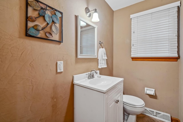 half bathroom featuring vanity, toilet, and baseboards