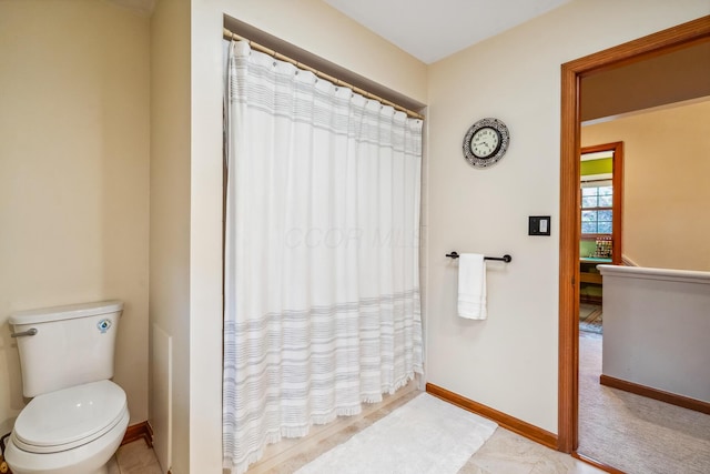bathroom with baseboards, toilet, and a shower with shower curtain