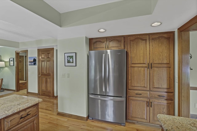7689 Godfrey Cir, Reynoldsburg, OH 43068 - kitchen with freestanding refrigerator, recessed lighting, brown cabinetry, light wood finished floors, and light stone countertops