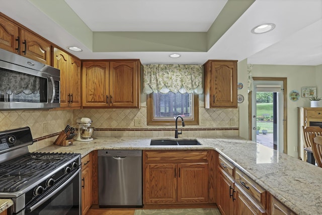 7689 Godfrey Cir, Reynoldsburg, OH 43068 - kitchen featuring appliances with stainless steel finishes, light stone countertops, backsplash, brown cabinetry, and recessed lighting
