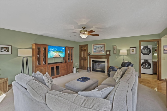 7689 Godfrey Cir, Reynoldsburg, OH 43068 - living room featuring stacked washer / drying machine, light carpet, ceiling fan, and a glass covered fireplace